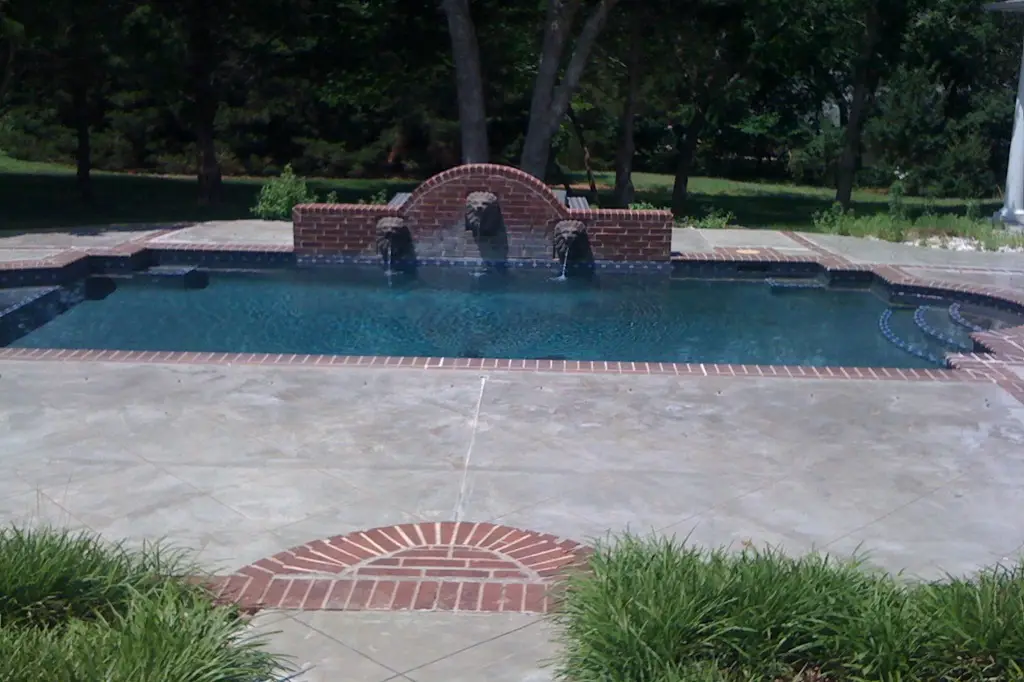 A serene daytime scene of a green pool, shimmering under the sun and surrounded by tropical plants.