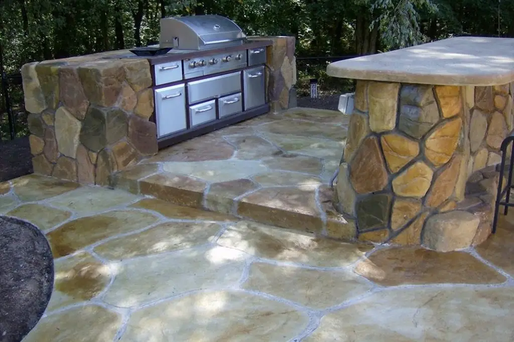 An elegant outdoor hardscape with a paved walkway, retaining walls, and a cozy fire pit, surrounded by lush greenery