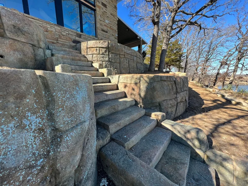 An elegant retaining wall with stairs leading up to a house