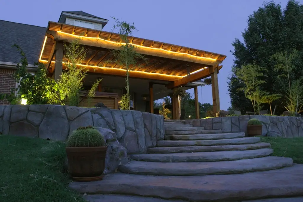 An outdoor patio at night with stairs leading up to the house