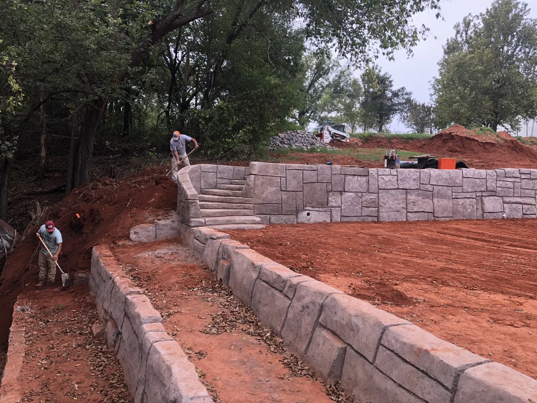 Two workers working together to clean and build a retaining wall Two workers working together to clean and build a retaining wall